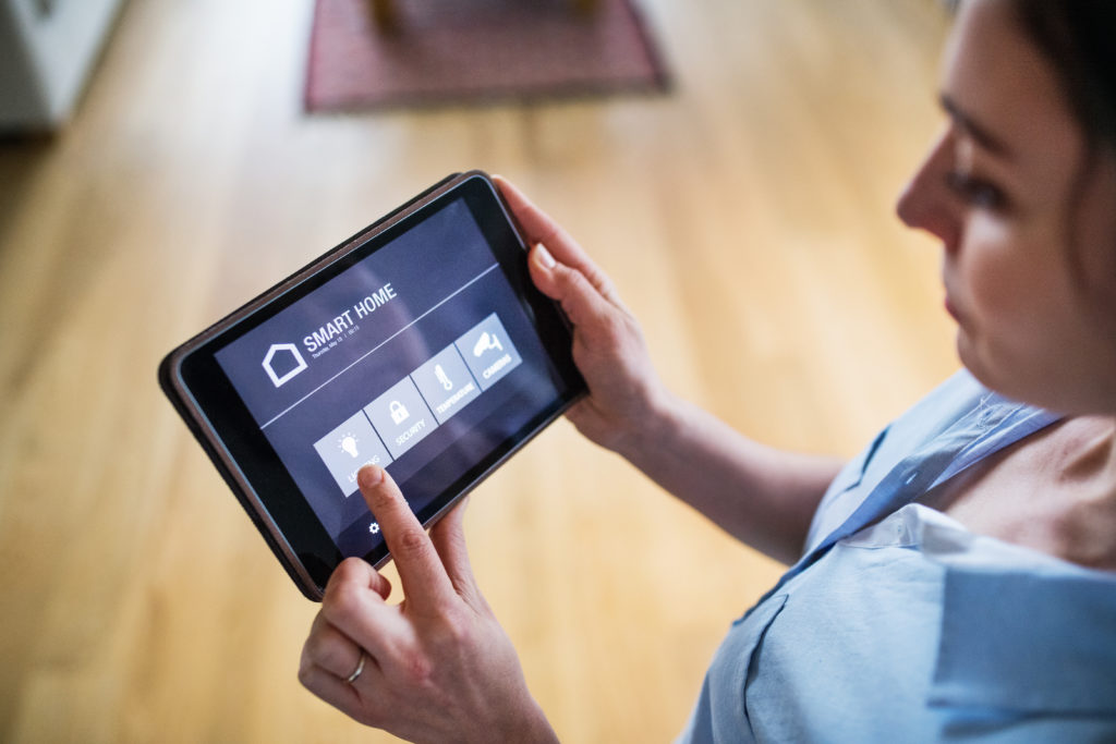 An unrecognizable woman holding a tablet with smart home control system.